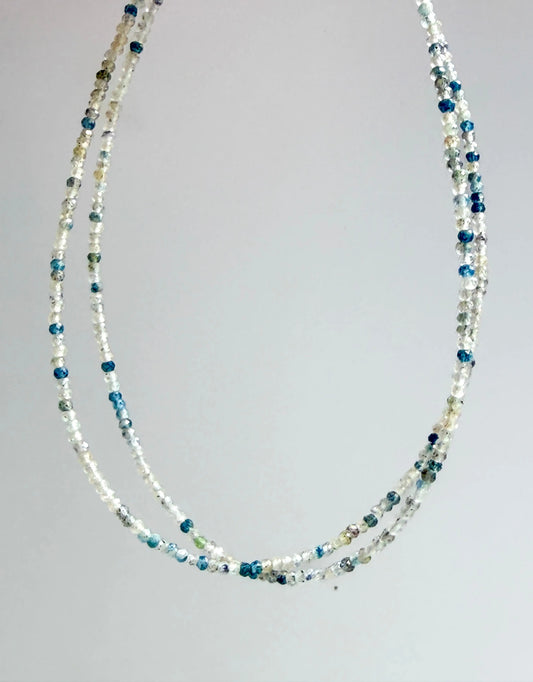 K2 Mineral with blue and gray multistrand beaded necklace on a gray background