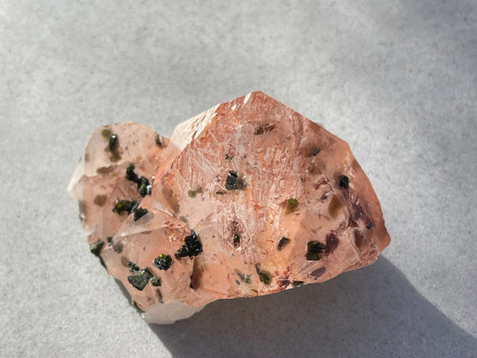 red crystal with green epidote inclusion on a grey background