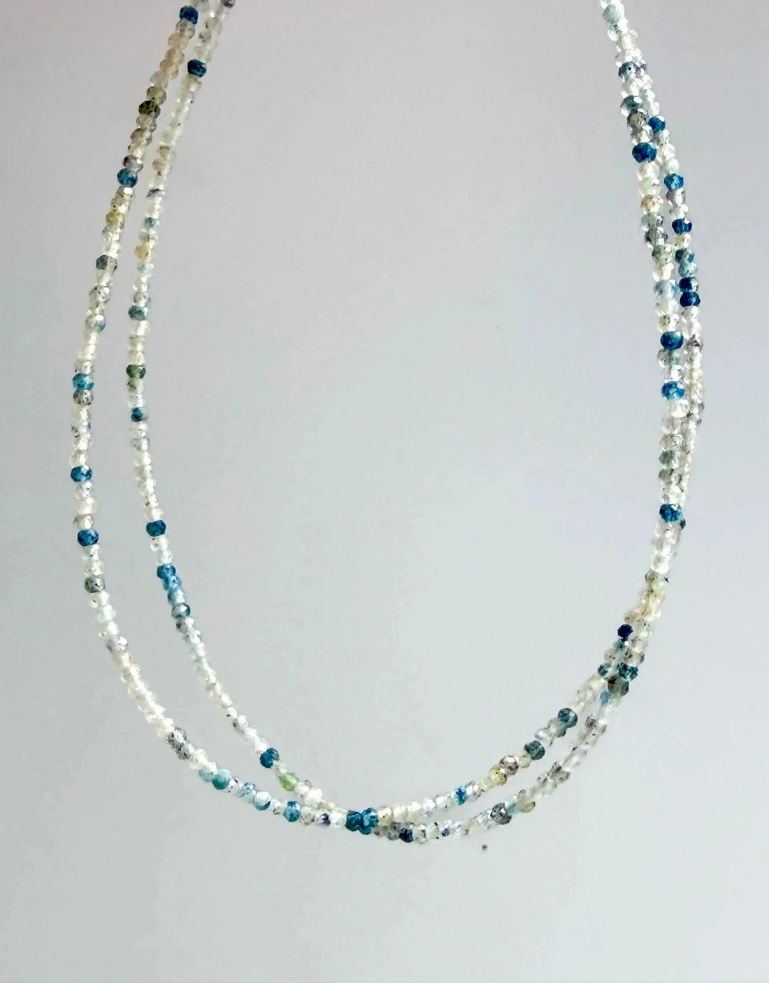 blue and clear quartz micro-faceted japanese minimalist jewelry on a grey background