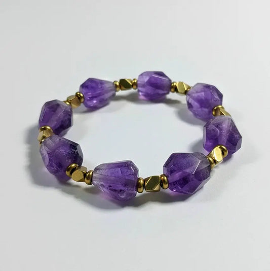 Purple beaded bracelet with gold accents on a light gray background