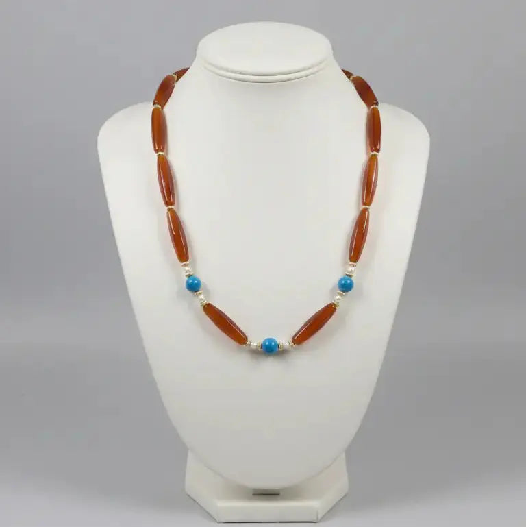 Necklace with brown beads and blue accents on a white mannequin bust against a gray background
