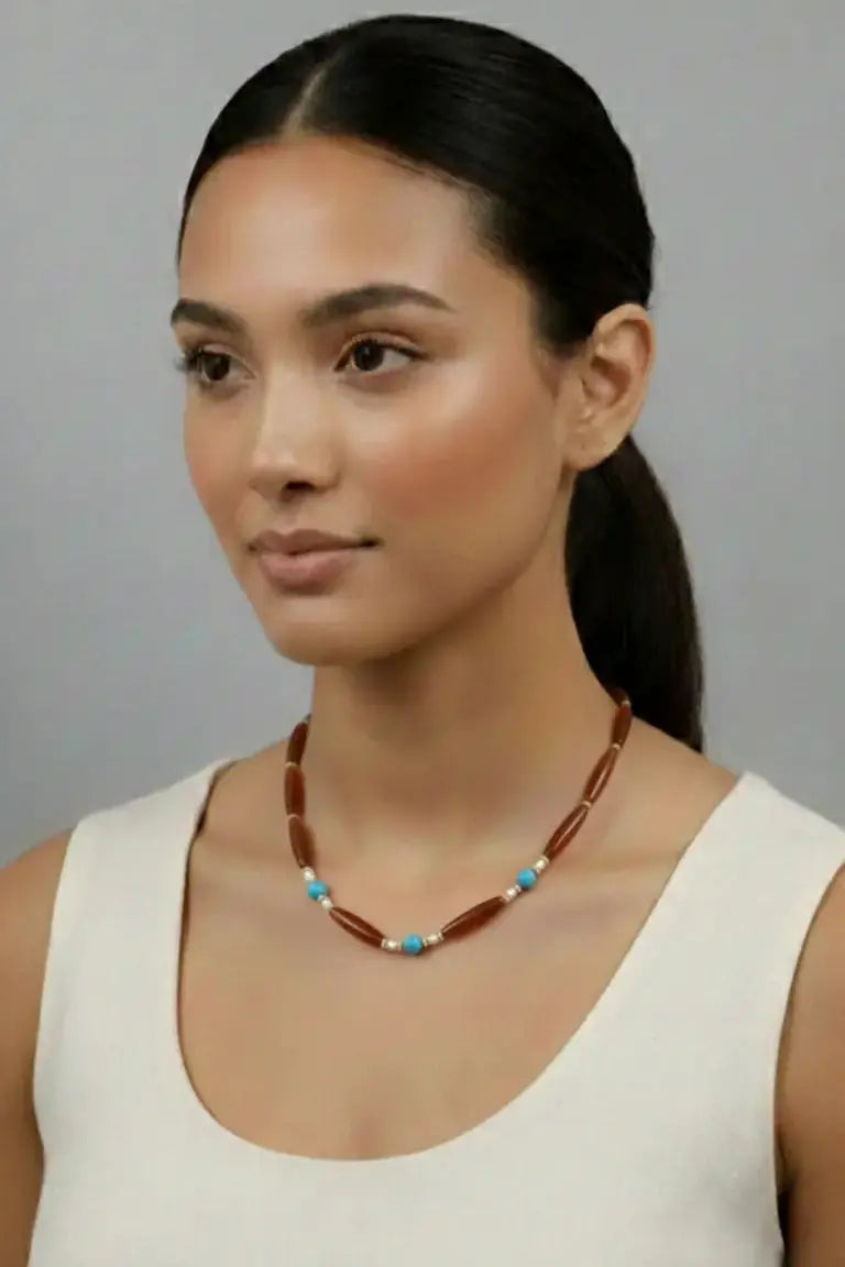 Woman wearing a beaded necklace against a gray background