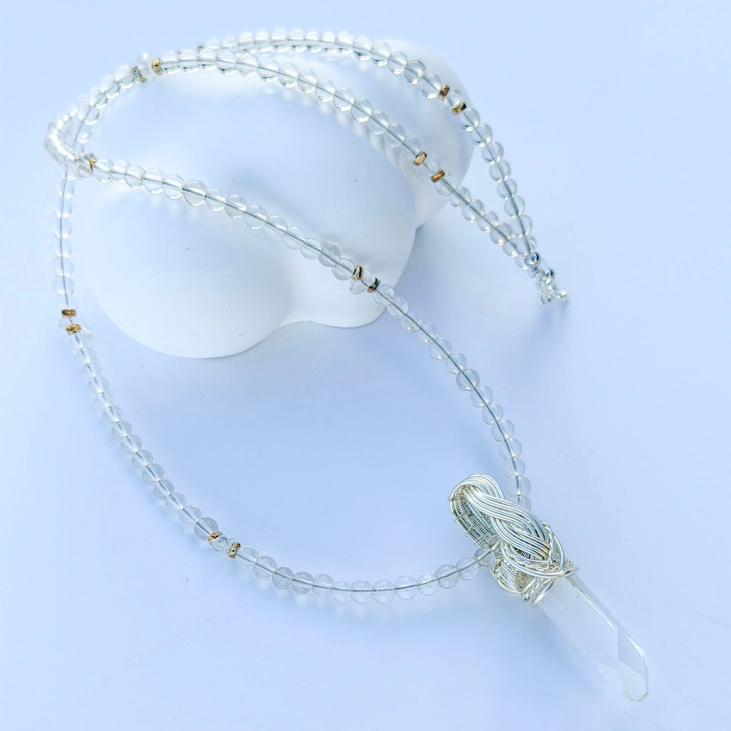 Necklace with clear beads and a tassel on a light blue background