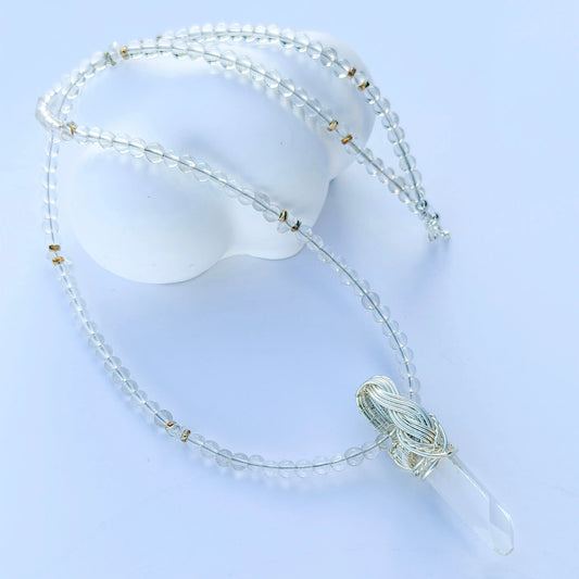 Necklace with clear beads and a tassel on a light blue background