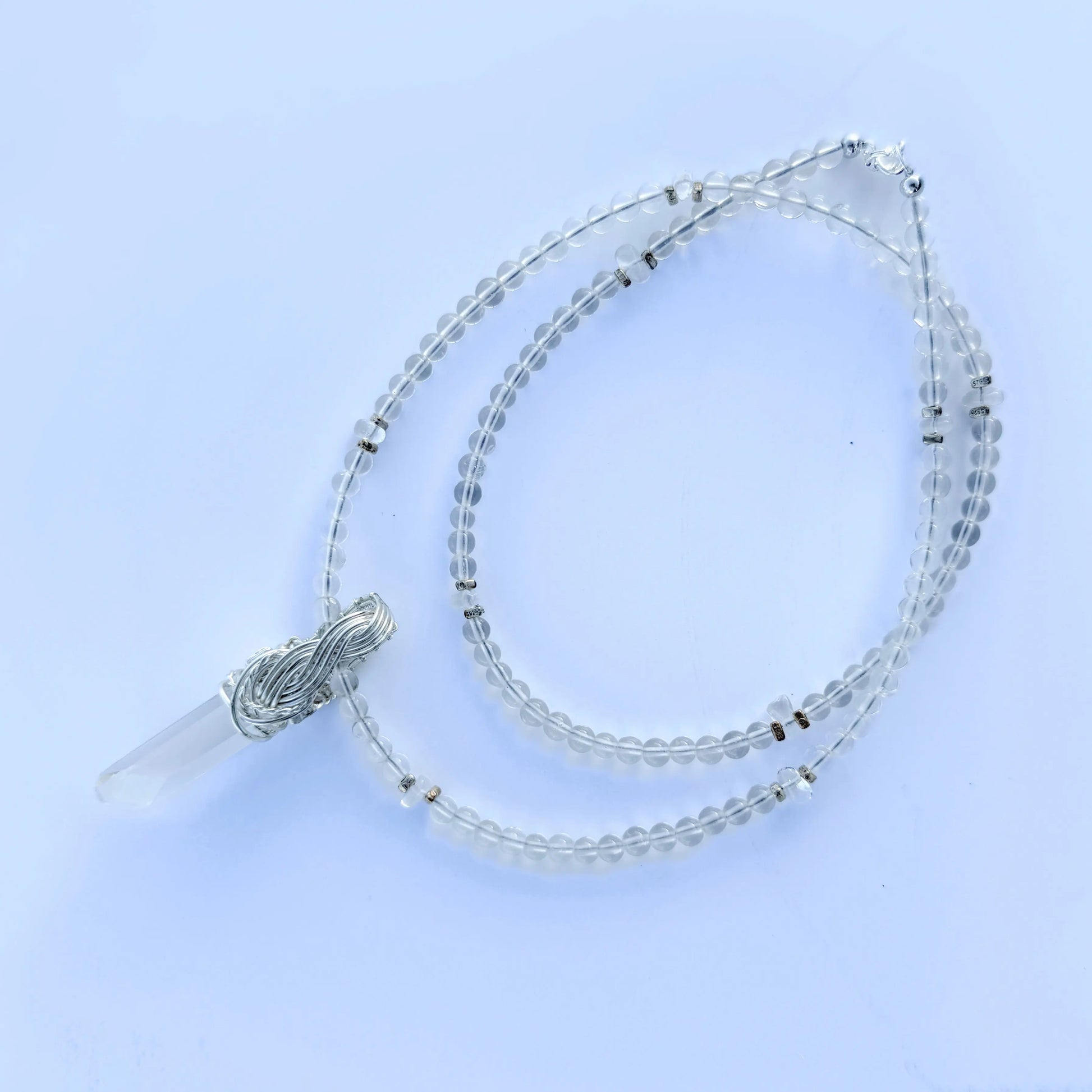 Beaded necklace with a clear pendant on a light blue background