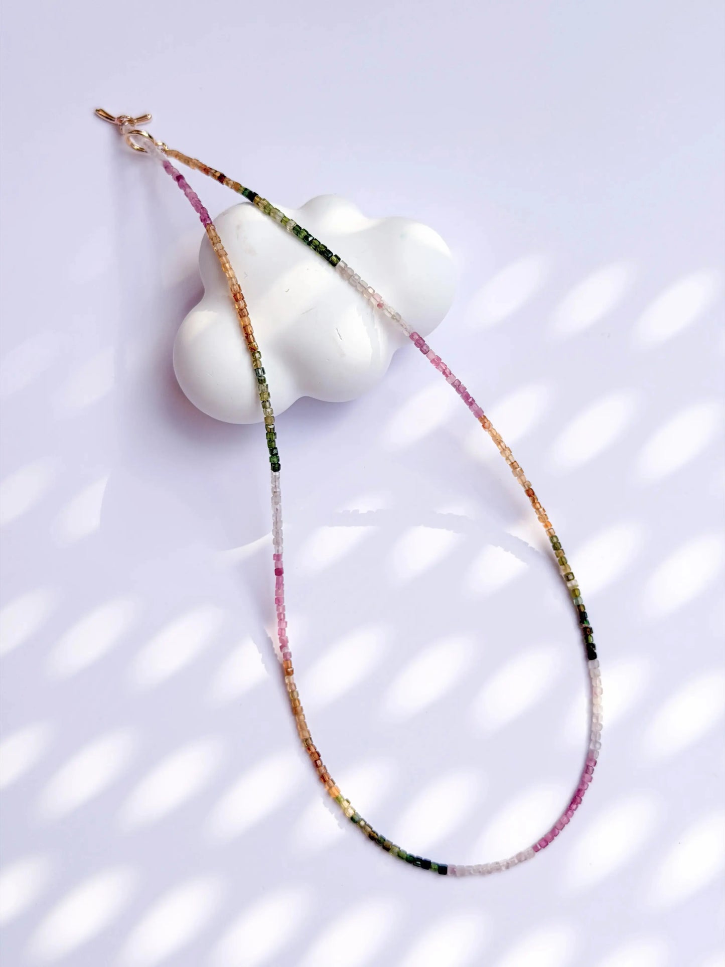 Rainbow tourmaline beaded necklace - pink, yellow, white, green gradient colors on white background