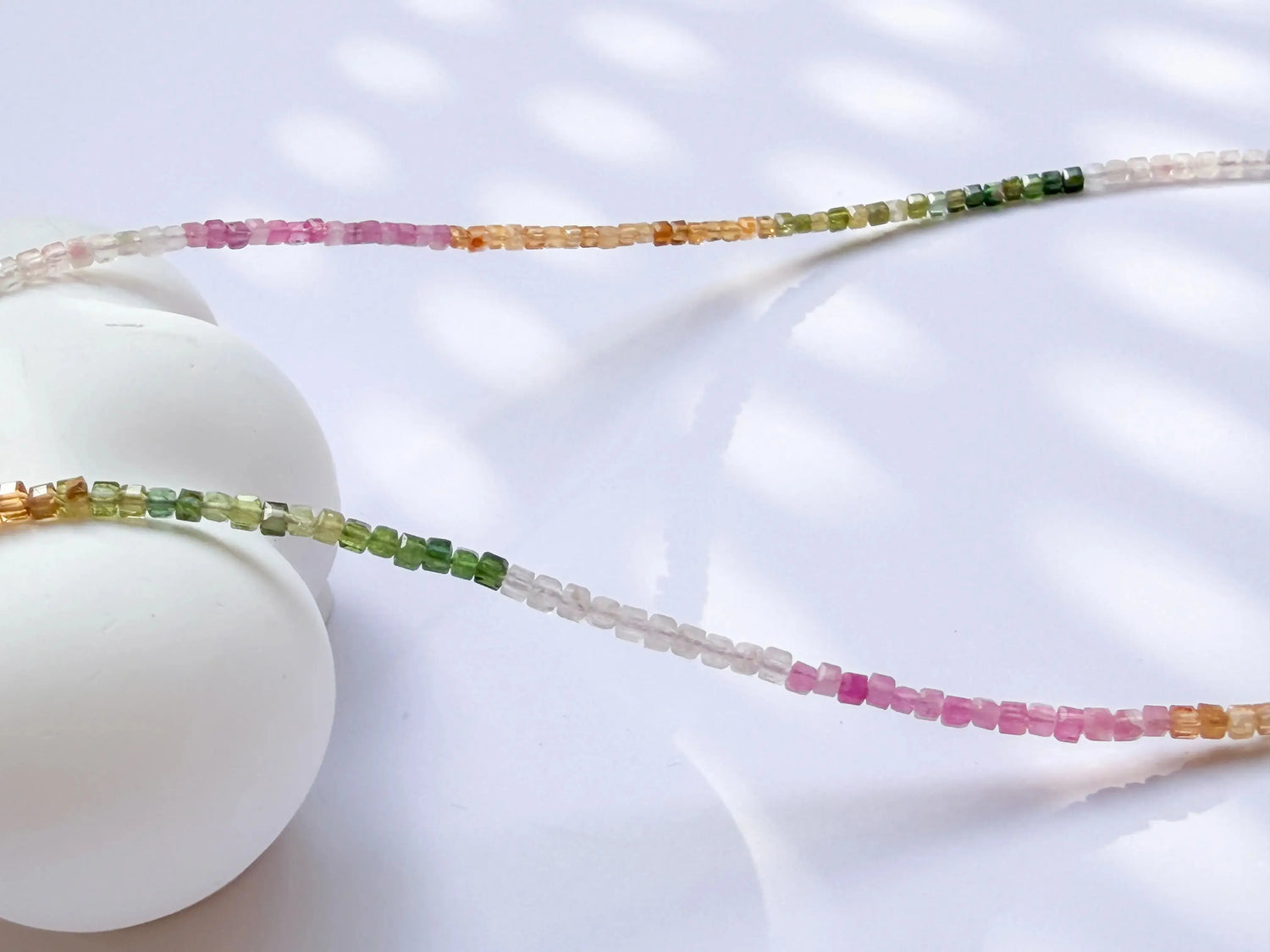 Rainbow tourmaline beaded necklace - pink, yellow, white, green gradient colors on white background