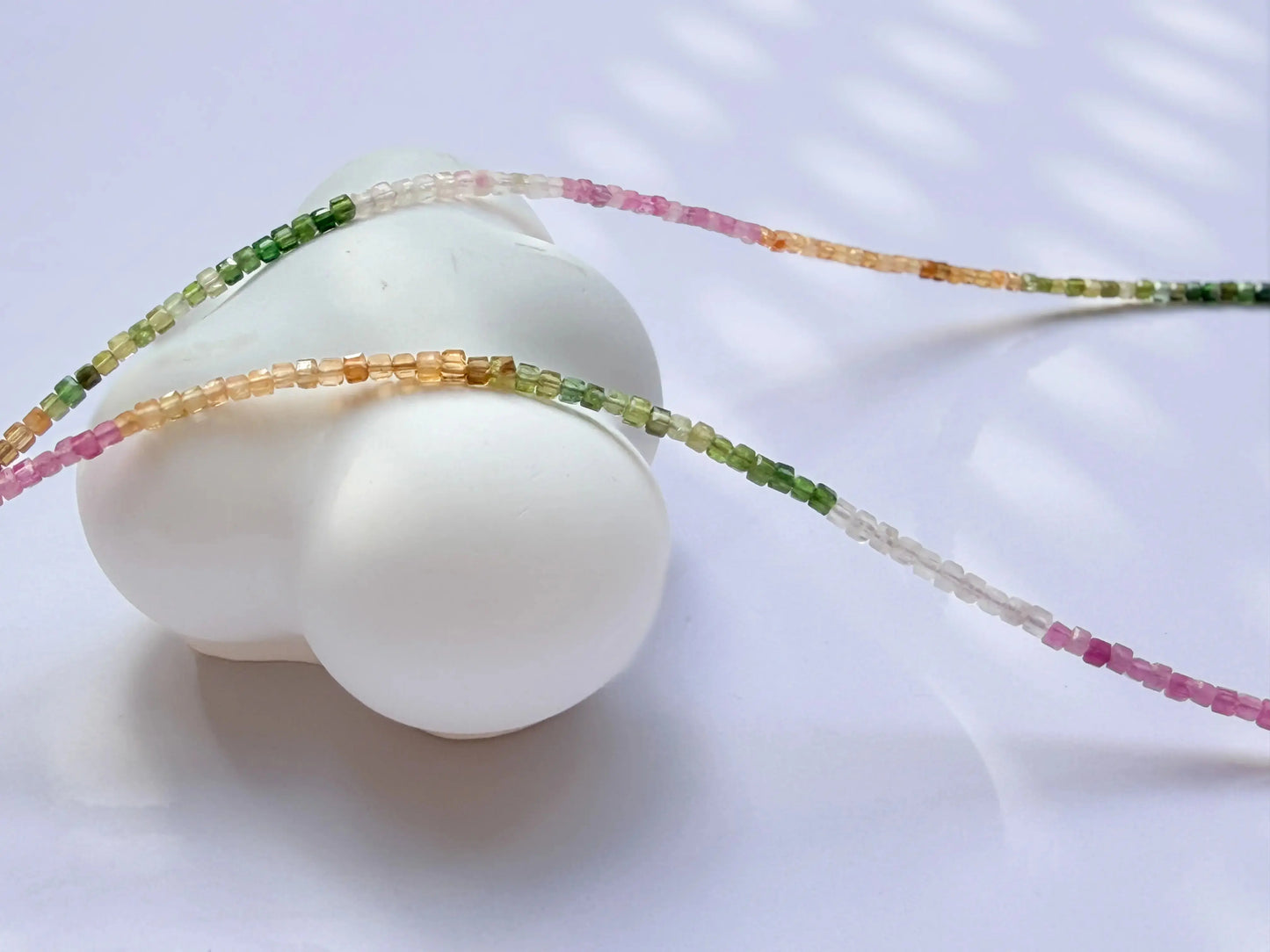 Rainbow tourmaline beaded necklace - pink, yellow, white, green gradient colors on white background