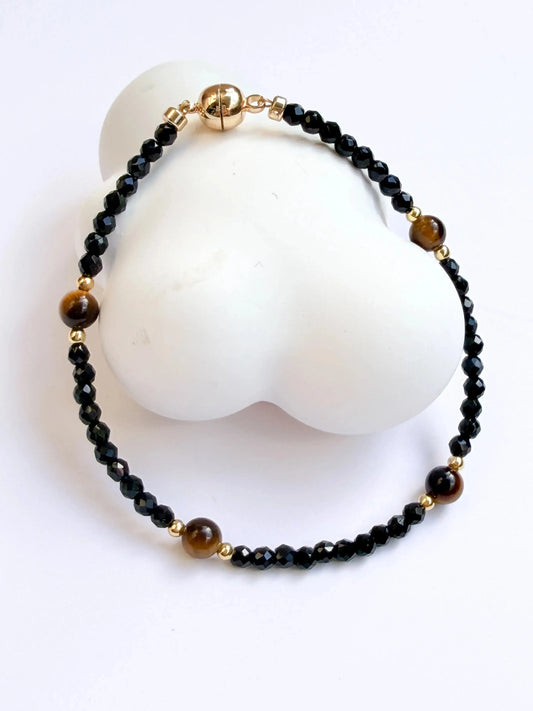 Black beaded bracelet with gold accents on a white stone surface