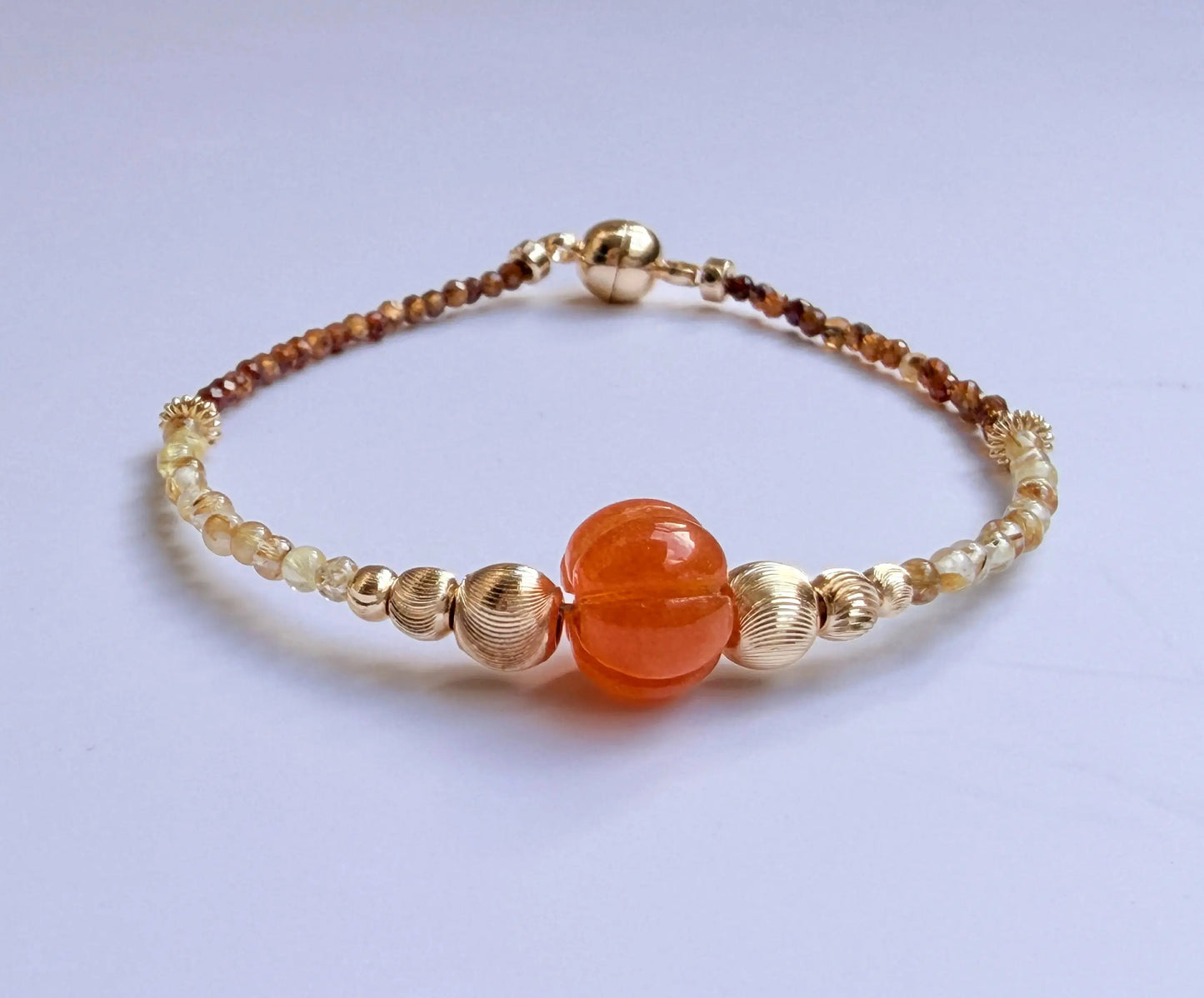 Japanese Minimalist Beaded Bracelet with Tiger Eye crystal, golden rutile crystal, orange, and gold elements on a white background