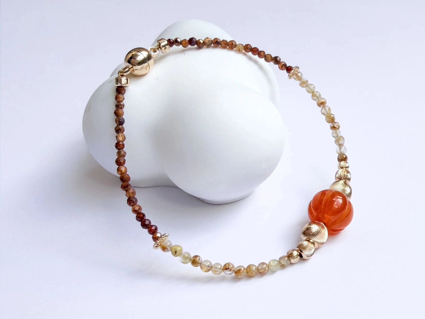 Japanese Minimalist Beaded Bracelet with Tiger Eye crystal, golden rutile crystal, orange, and gold elements on a white background