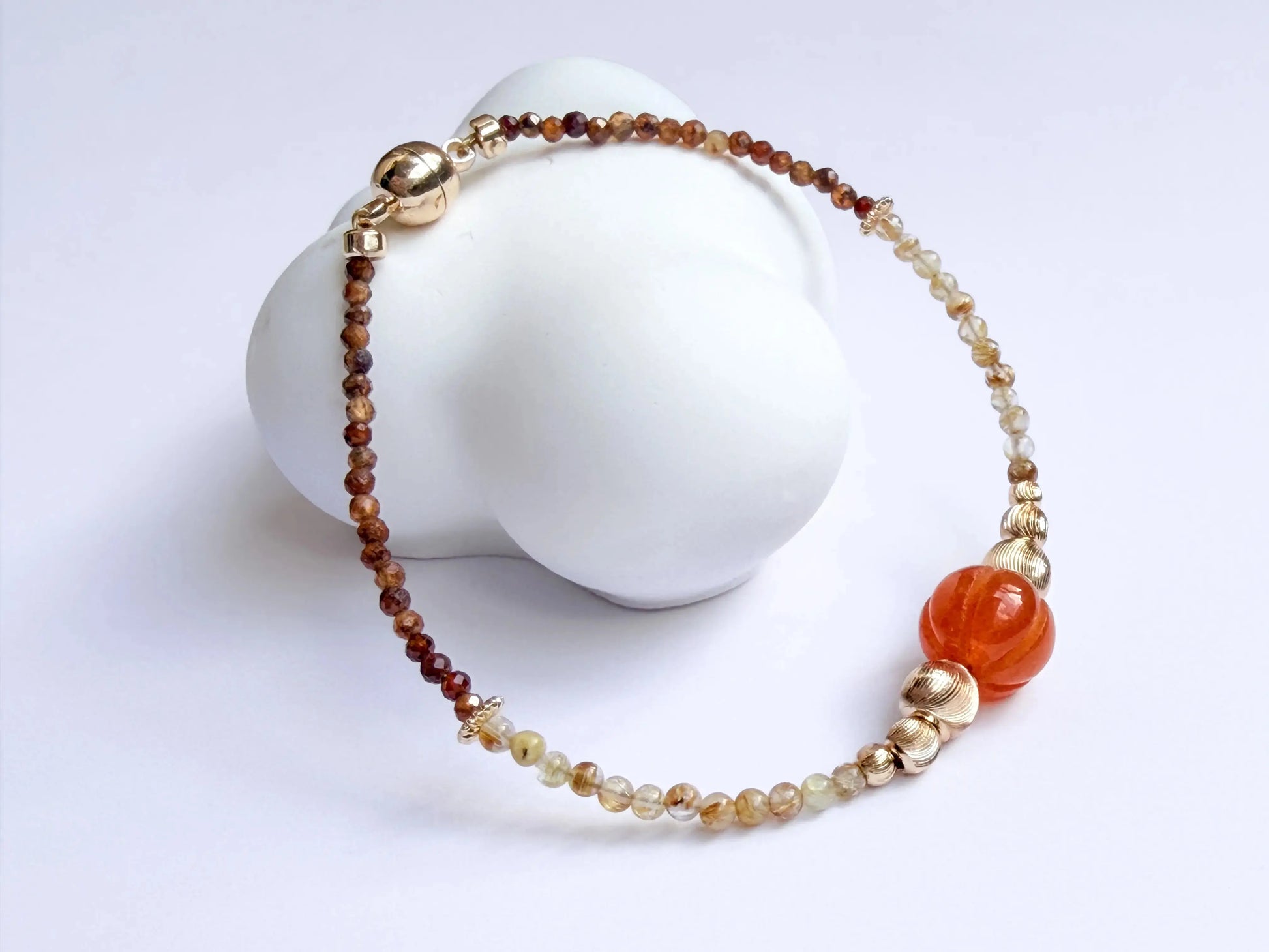Japanese Minimalist Beaded Bracelet with Tiger Eye crystal, golden rutile crystal, orange, and gold elements on a white background