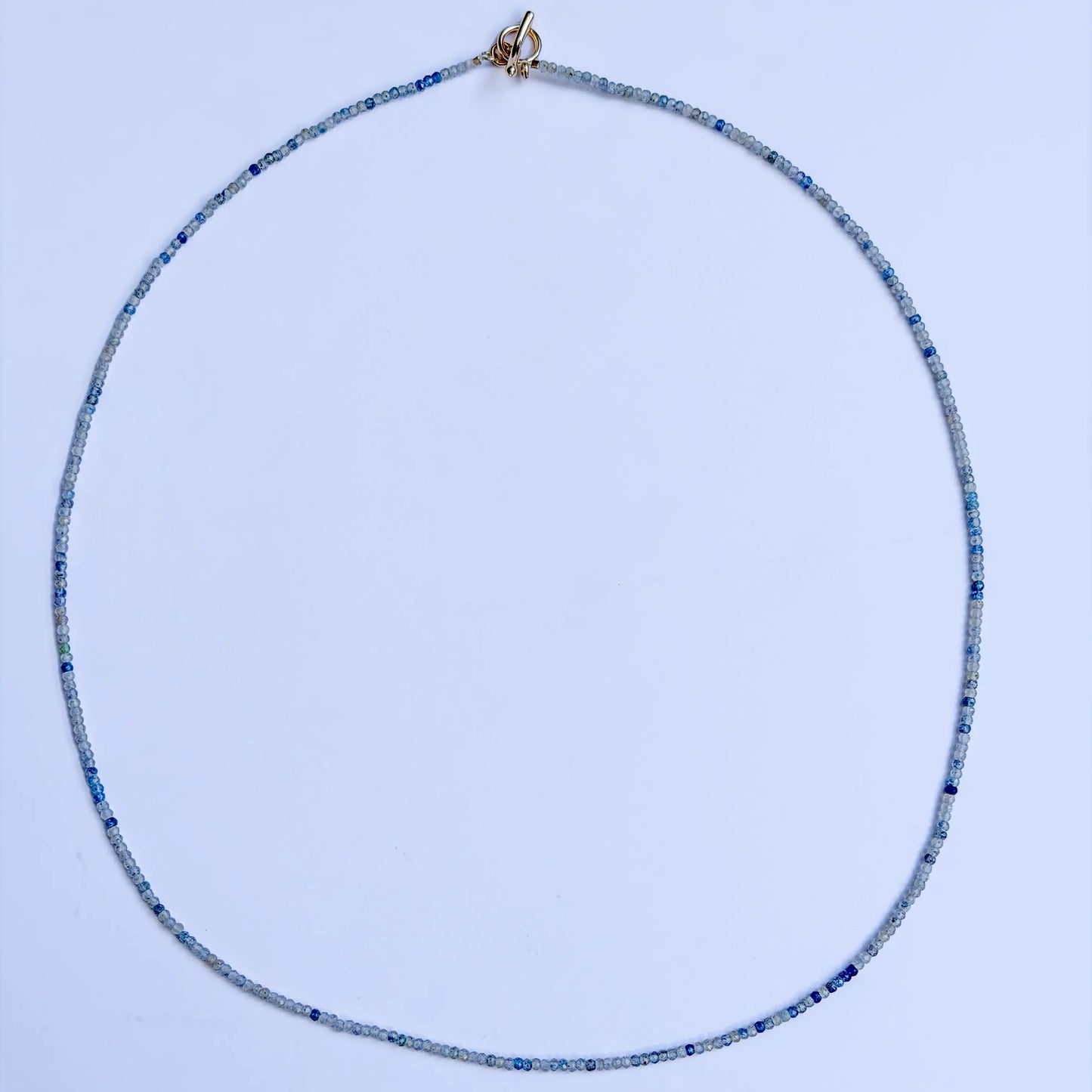 K2 mineral necklace with blue and white beads on a light blue background