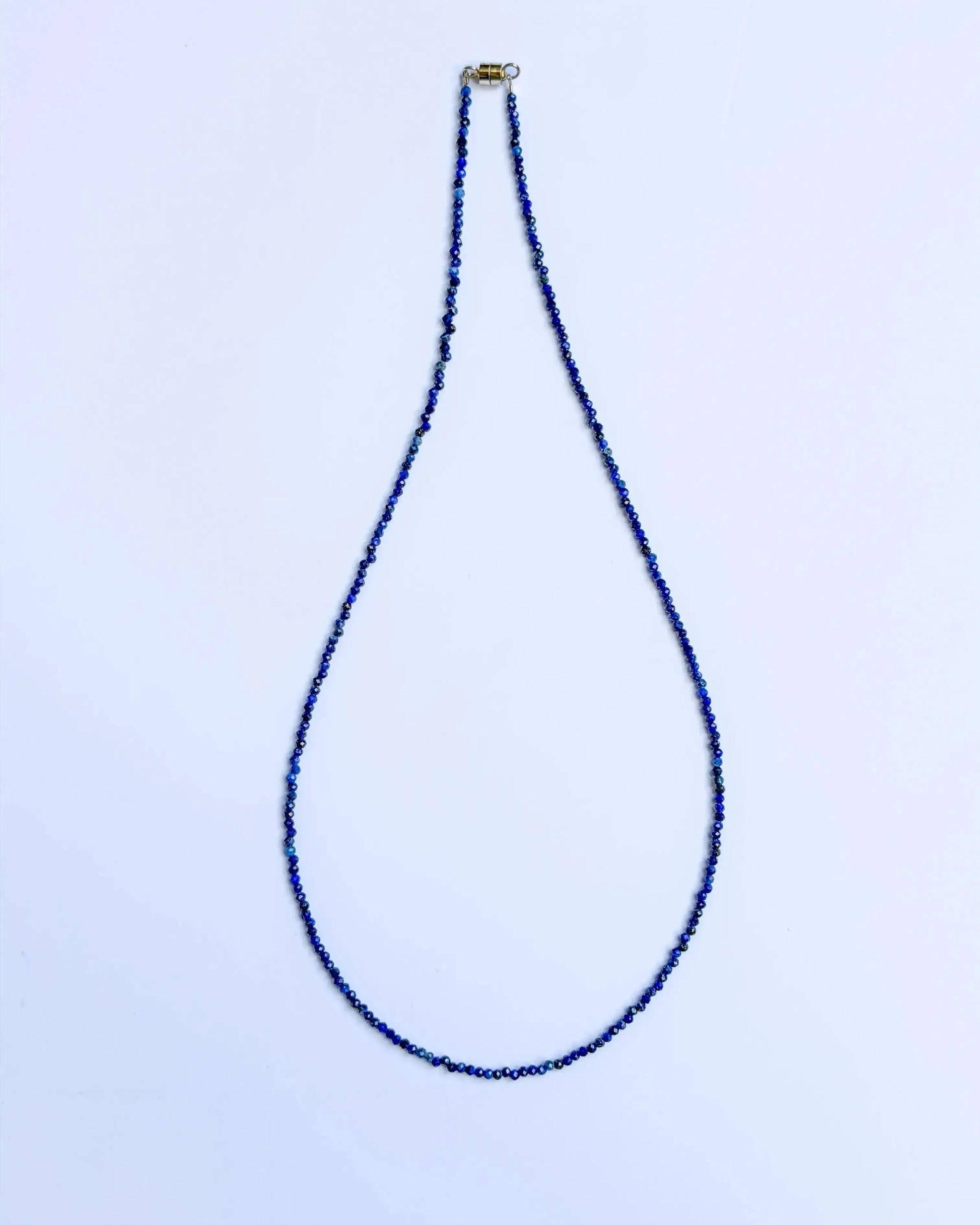 lapis lazuli jewelry - Blue beaded necklace on a light blue background