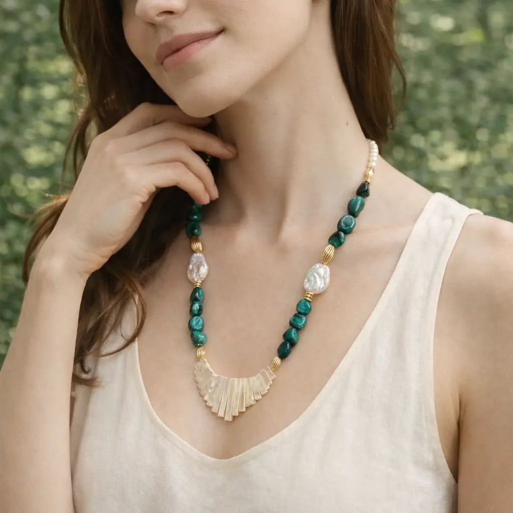 Woman wearing a necklace with a green and gold design against a blurred natural background