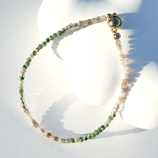 Bracelet with green and white jade beads on a white mannequin bust against a light blue background