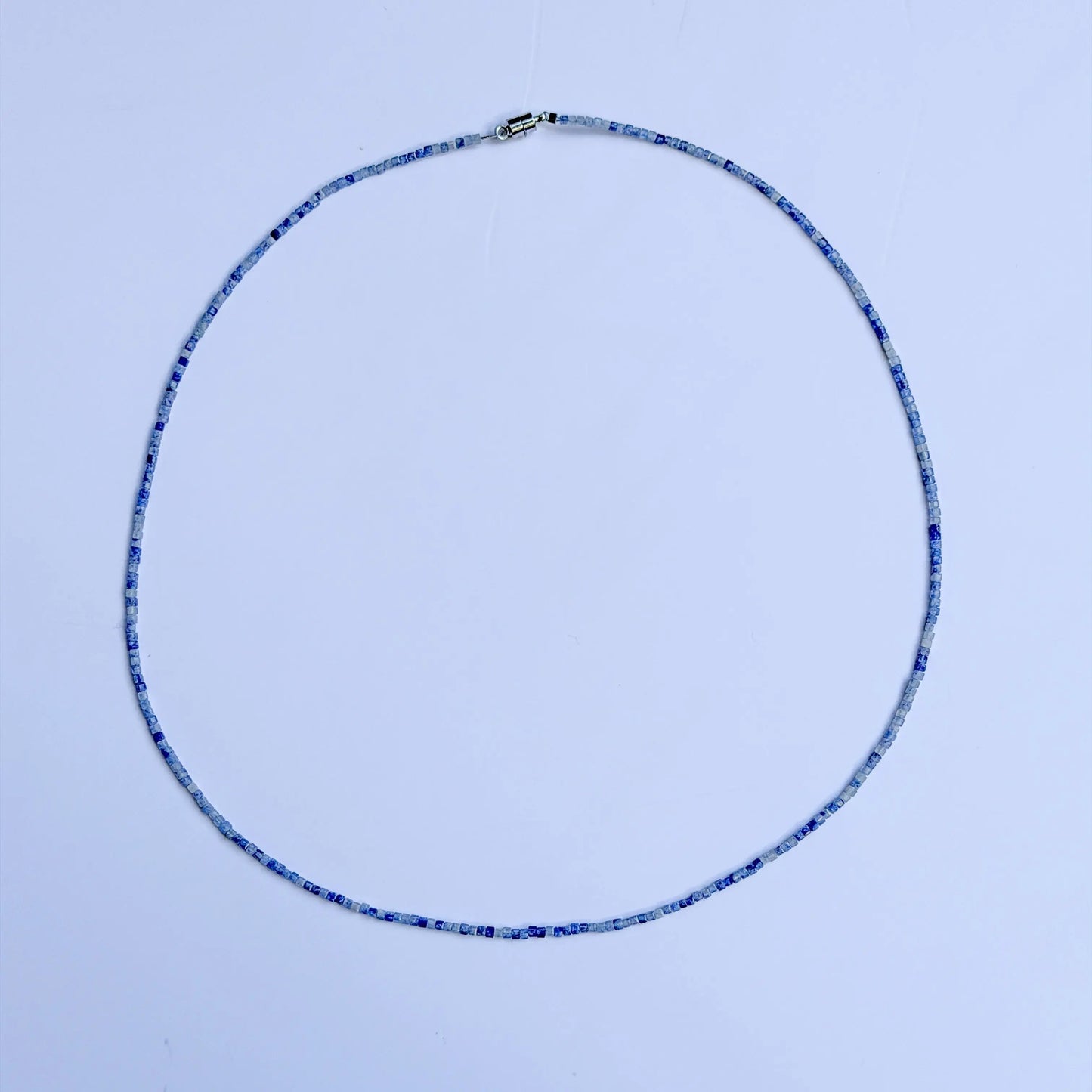 Sodalite crystal with blue bead necklace on a white background
