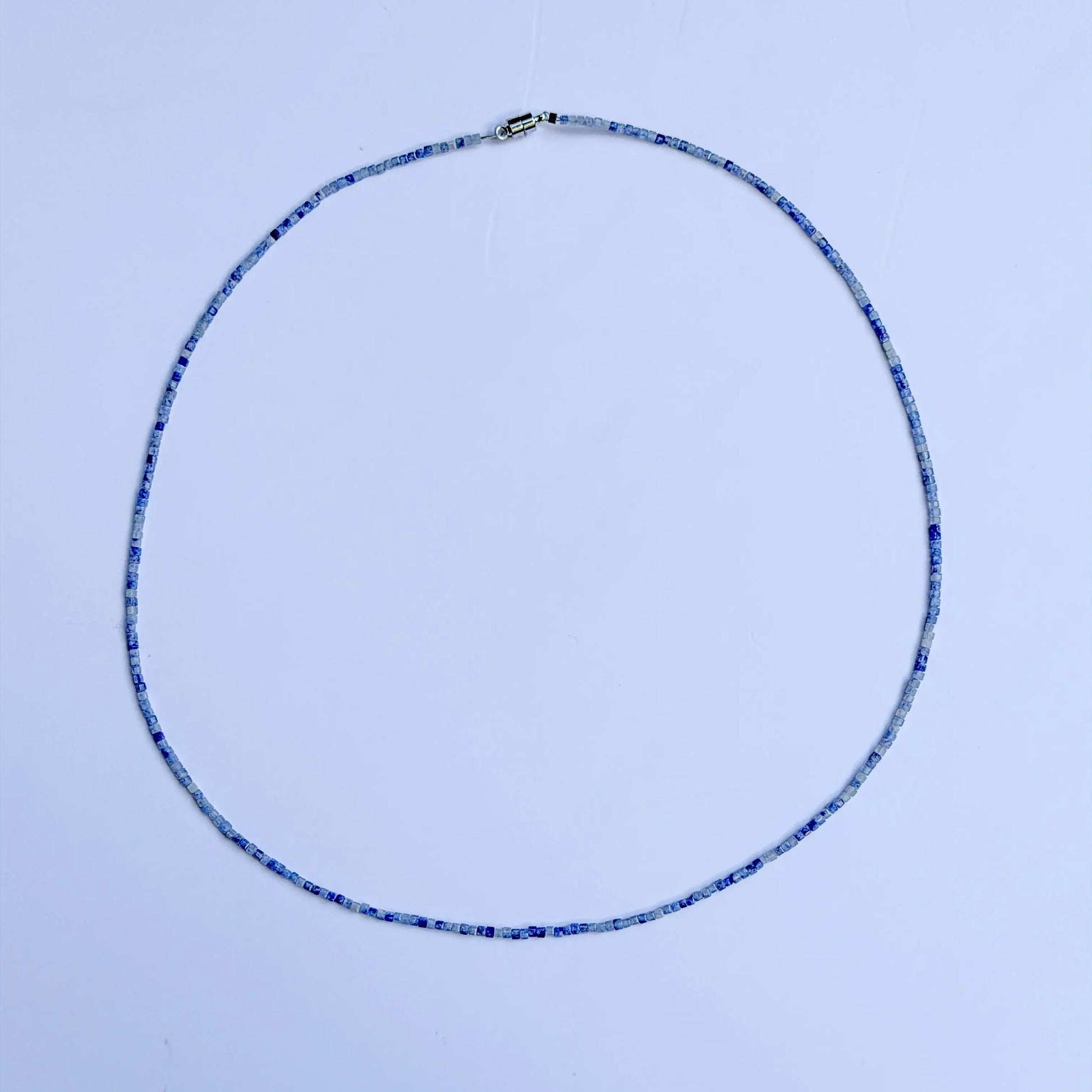 Sodalite crystal with blue bead necklace on a white background