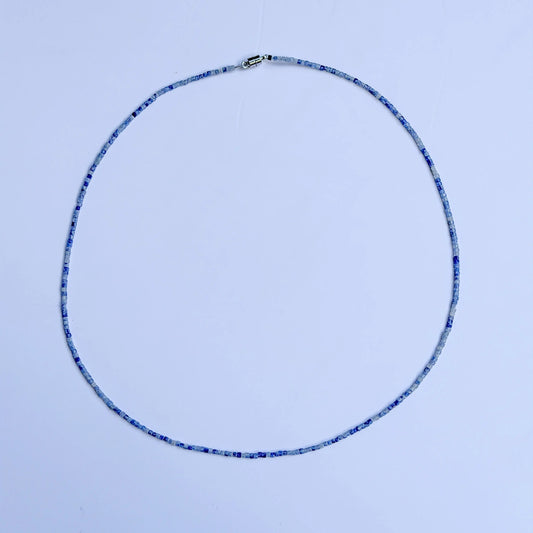 Sodalite crystal with blue bead necklace on a white background