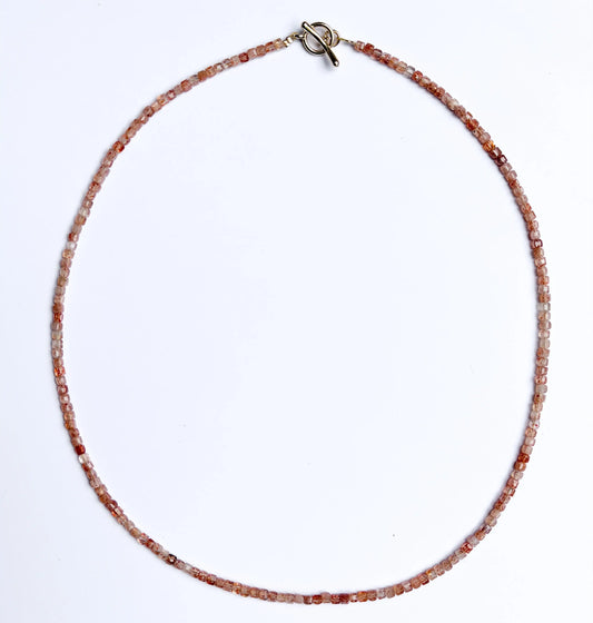 Sunstone Necklace with small orange beads on a white background