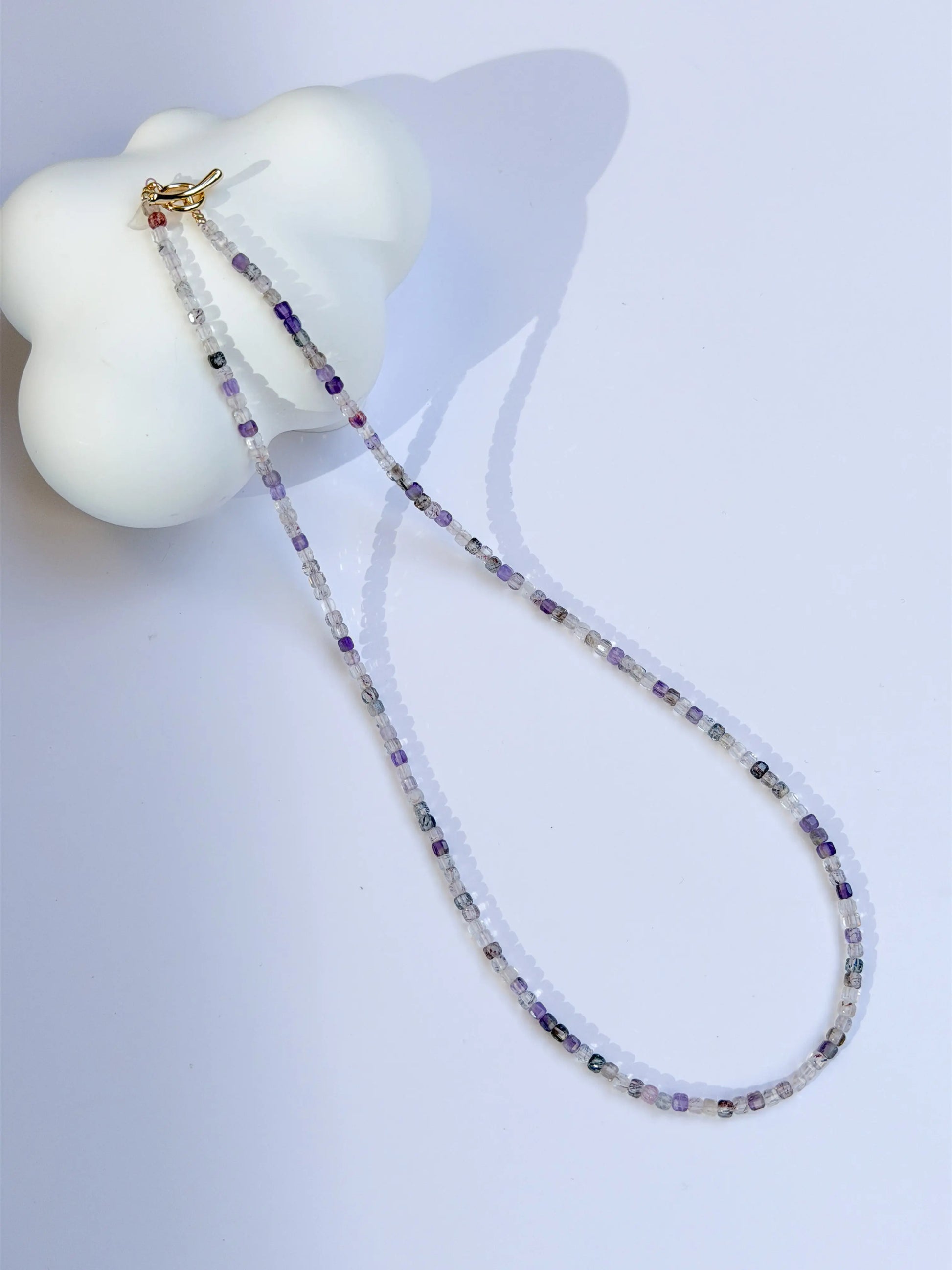 Super 7 Amethyst Beaded necklace on a white surface with a white object in the background
